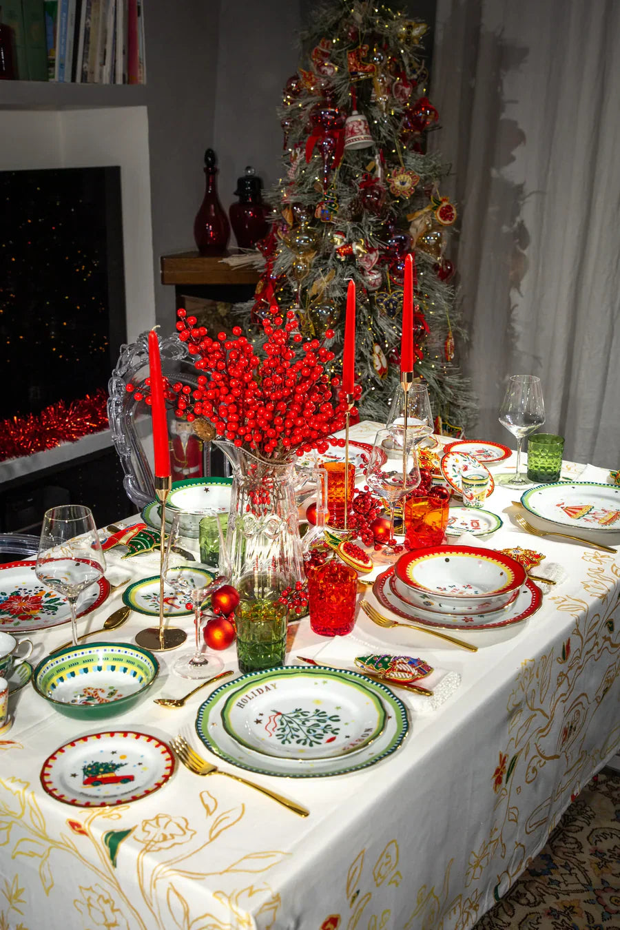 Mamma Mia Xmas festive dining table with red-green porcelain plates, glassware and candles, Christmas tree — Amprio Milano.