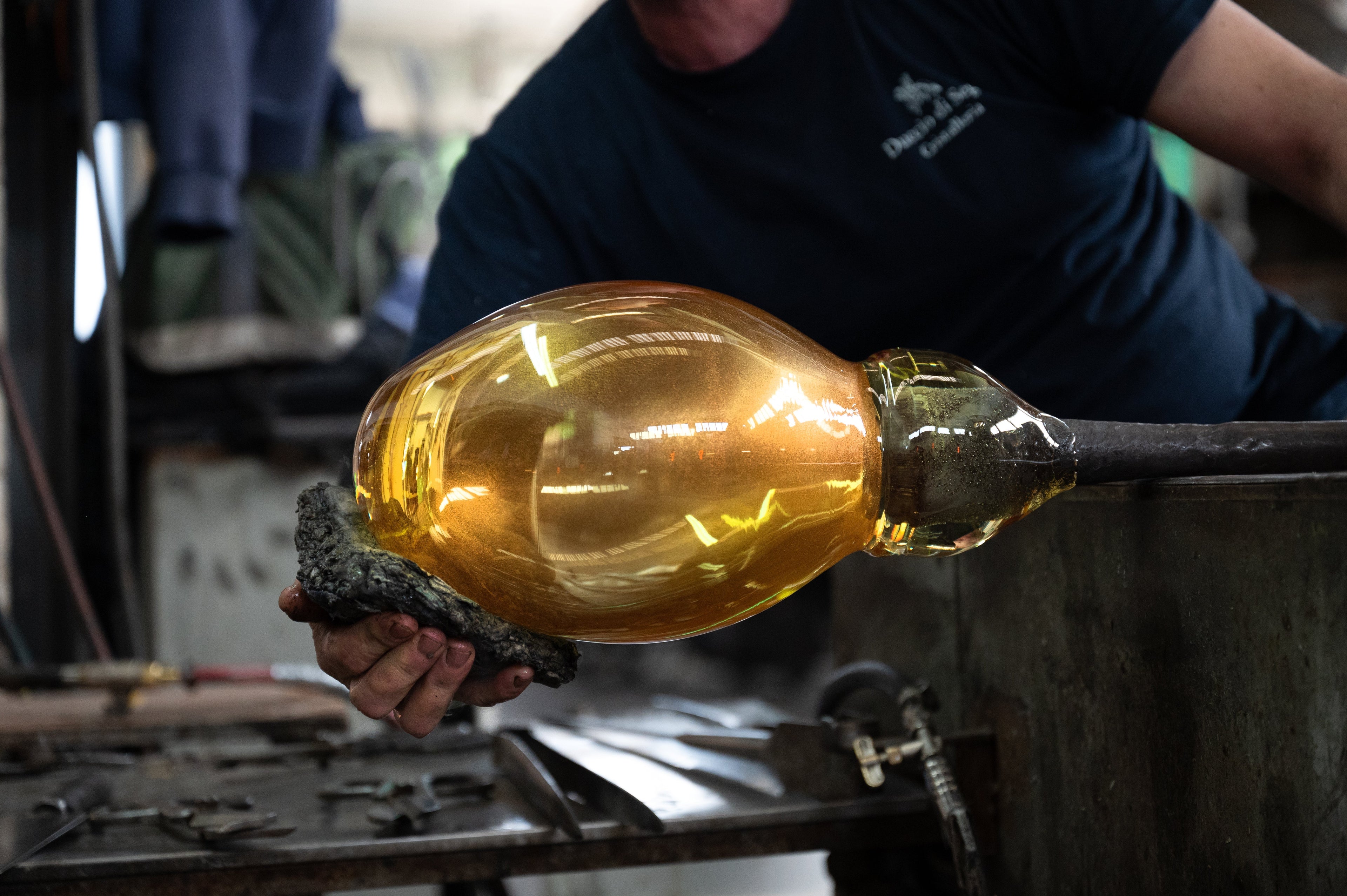 Master glassmaker shaping a Duccio Di Segna amber crystal sculpture at the Colle di Val d'Elsa atelier furnace in Tuscany
