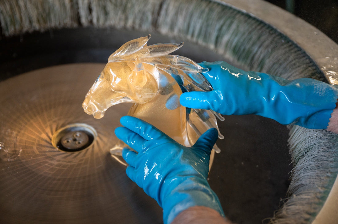 Craftsman's hands rinsing an amber crystal horse head sculpture in the Duccio Di Segna atelier