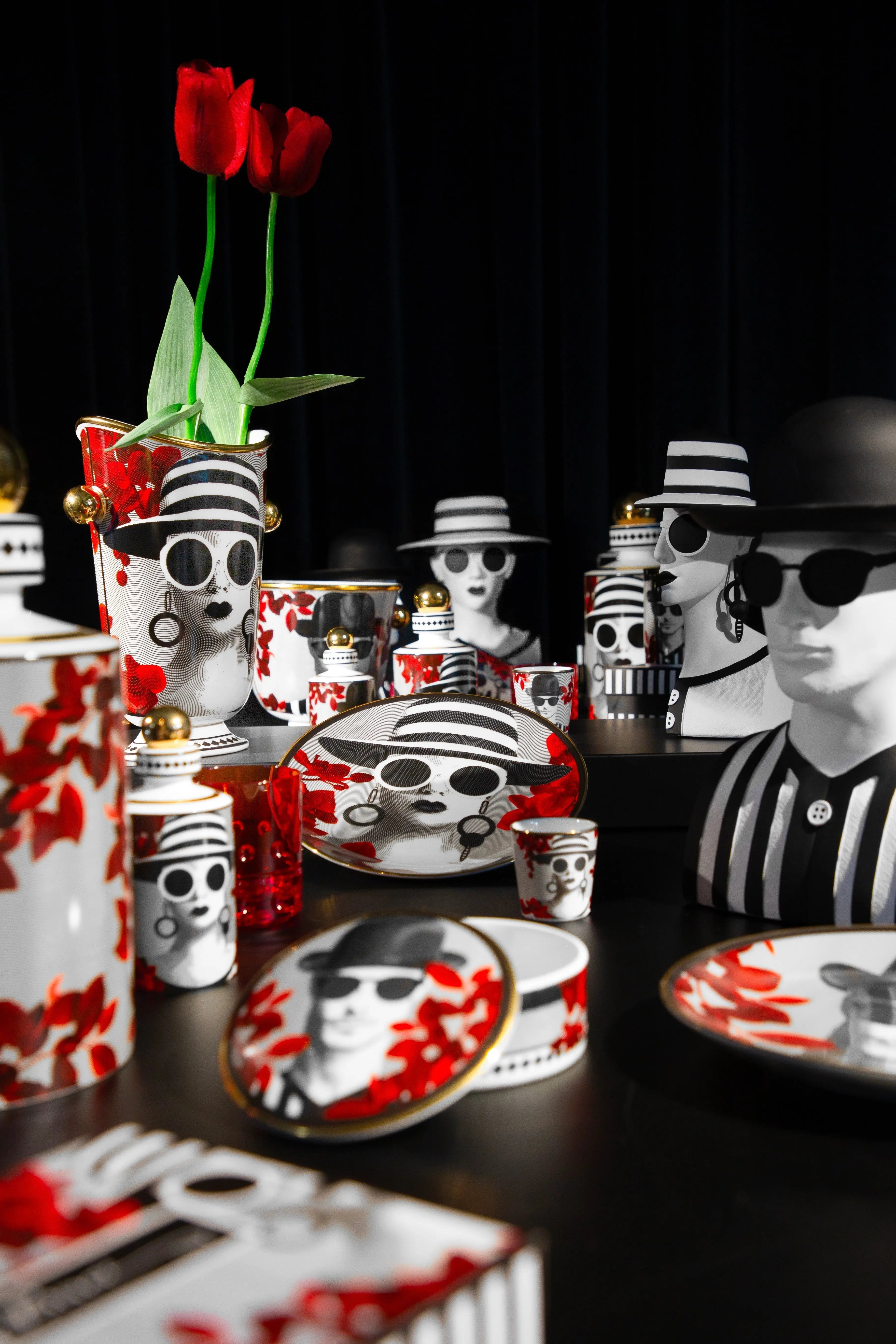 Gli Inseparabili collection — black-and-white face motif tableware with red petals and gold accents by Amprio Milano