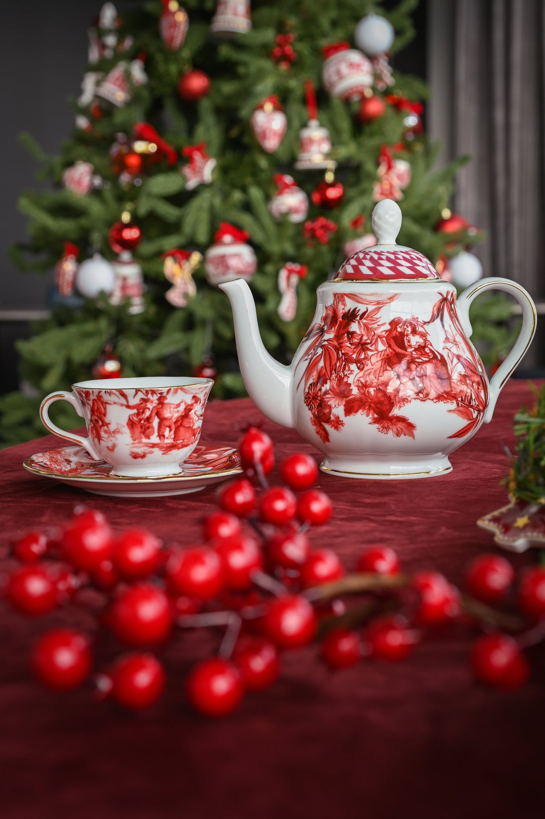 Le Rouge porcelain teapot and cup with red toile pattern on a festive table, Christmas tree behind — Amprio Milano