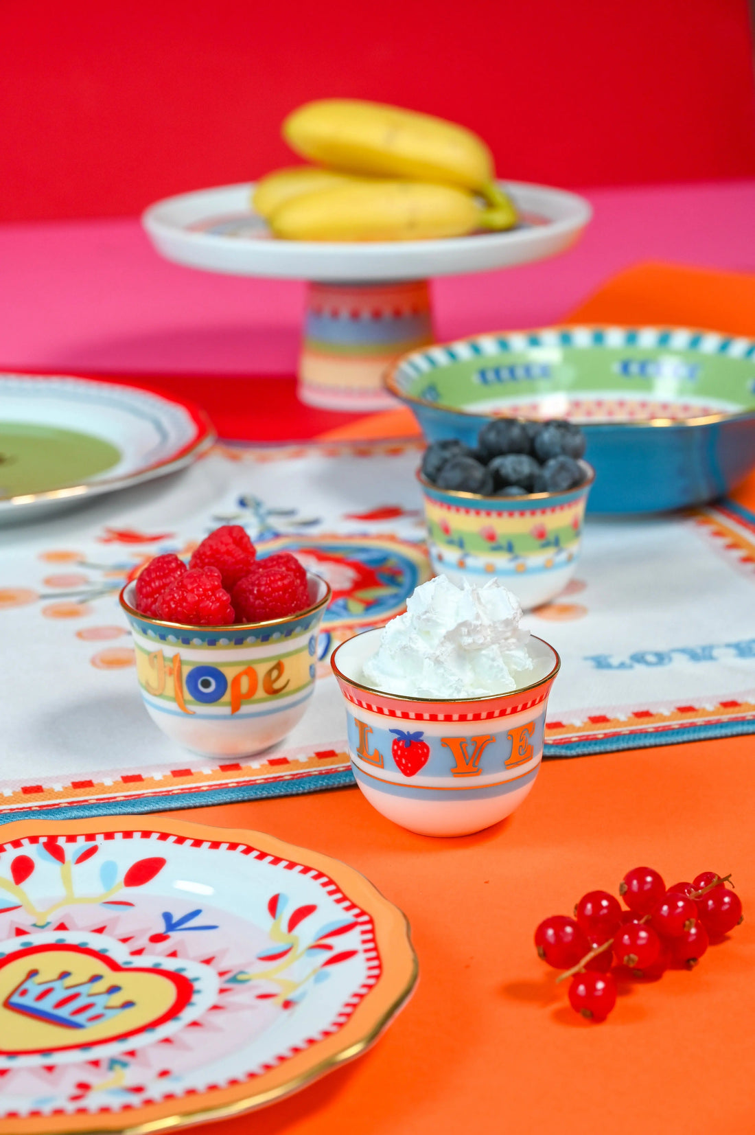 Hand-painted Mamma Mia Arabic coffee cups and small porcelain bowls styled with fruit and cream on a bright tablescape — Italian porcelain composed for Gulf hosting.