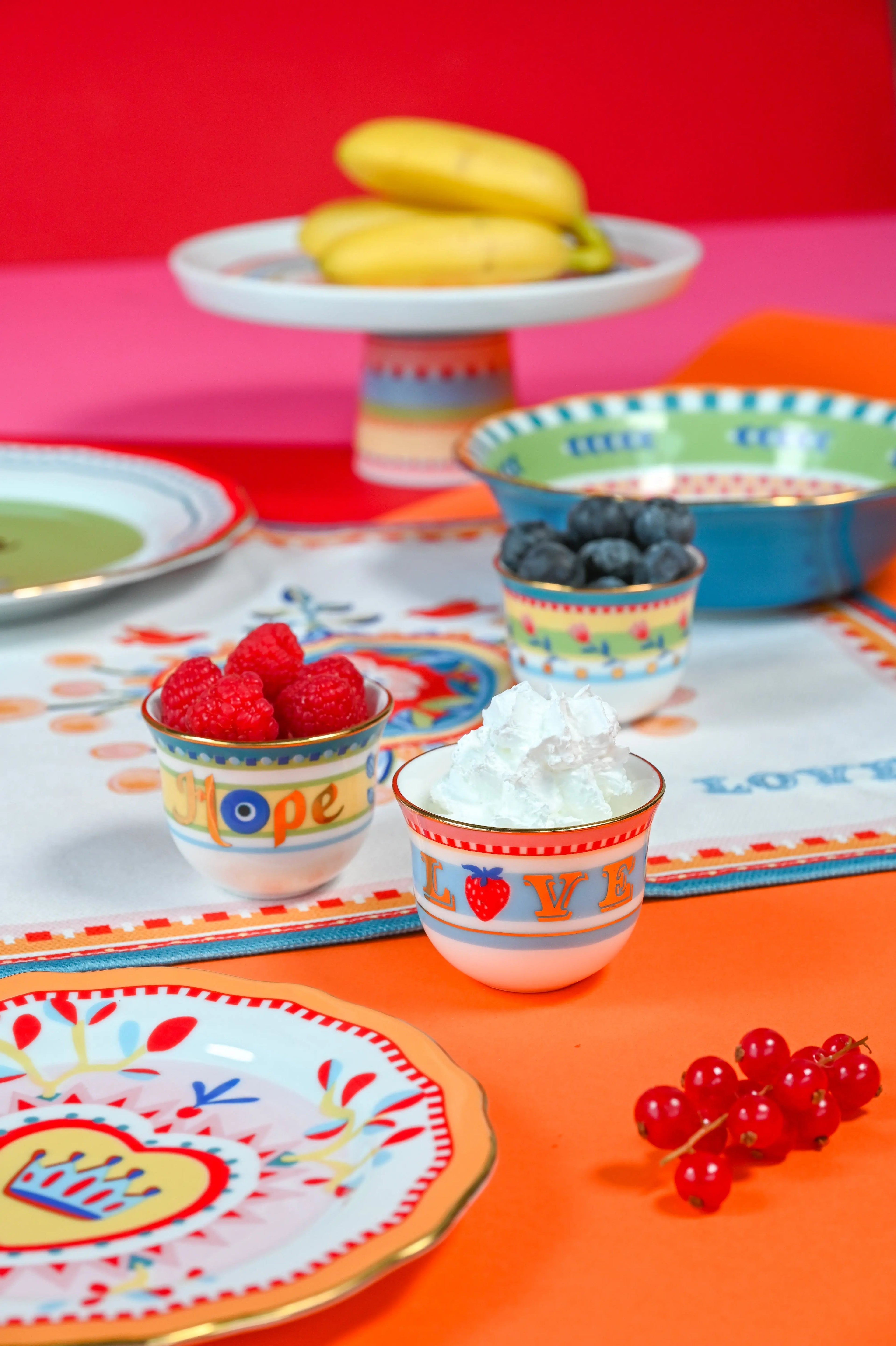 Hand-painted Mamma Mia Arabic coffee cups and small porcelain bowls styled with fruit and cream on a bright tablescape — Italian porcelain composed for Gulf hosting.