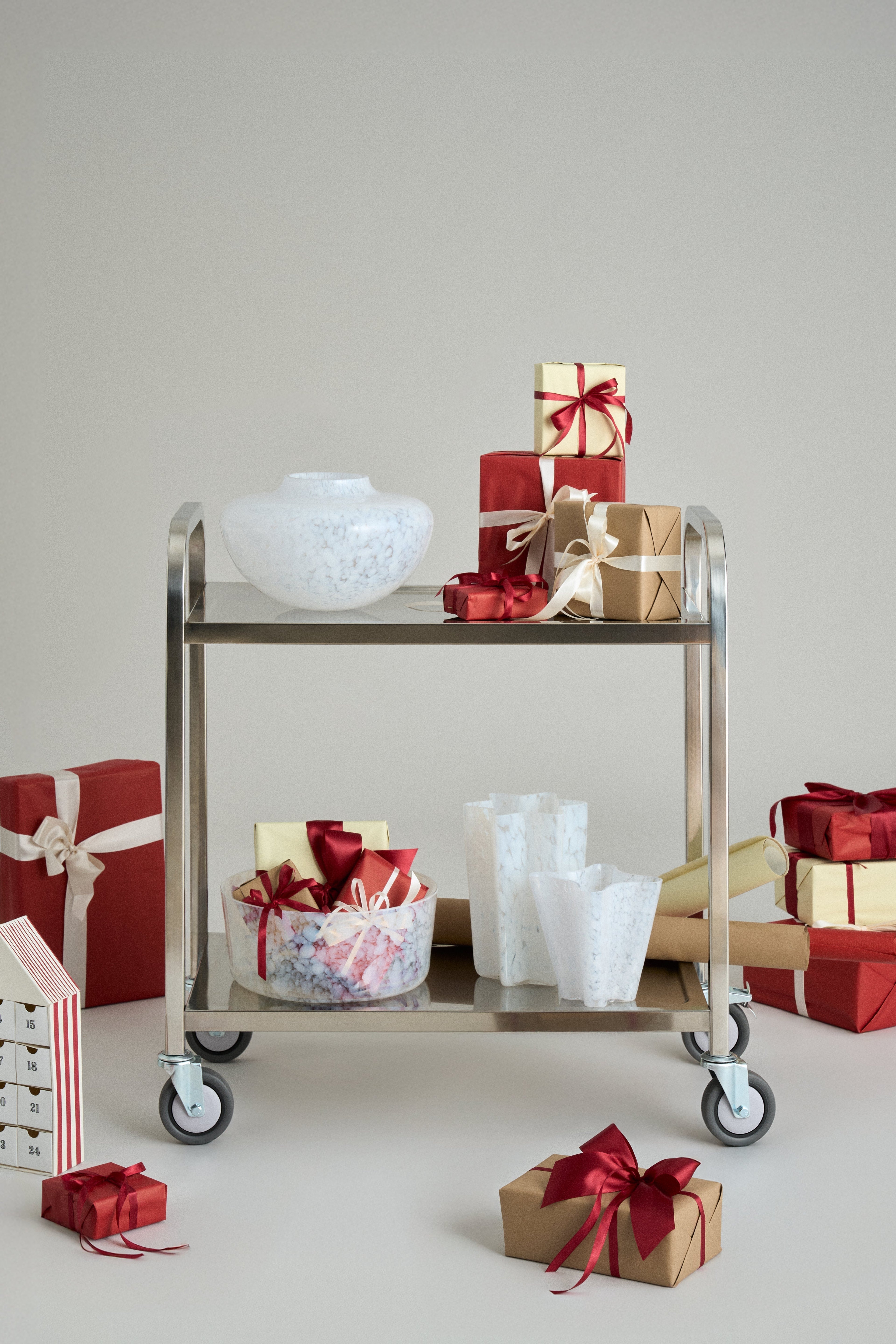 A white mouth-blown Murano Olla vase on a serving trolley surrounded by gift-wrapped boxes — a one-of-a-kind Italian design gift