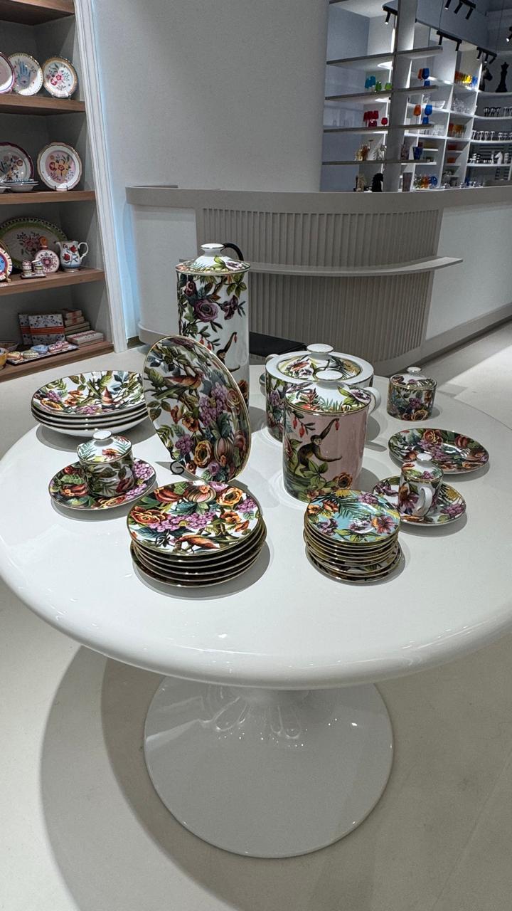 Italian porcelain dinner service with jungle and bird motifs on a round white pedestal table in a Riyadh villa formal salon setting