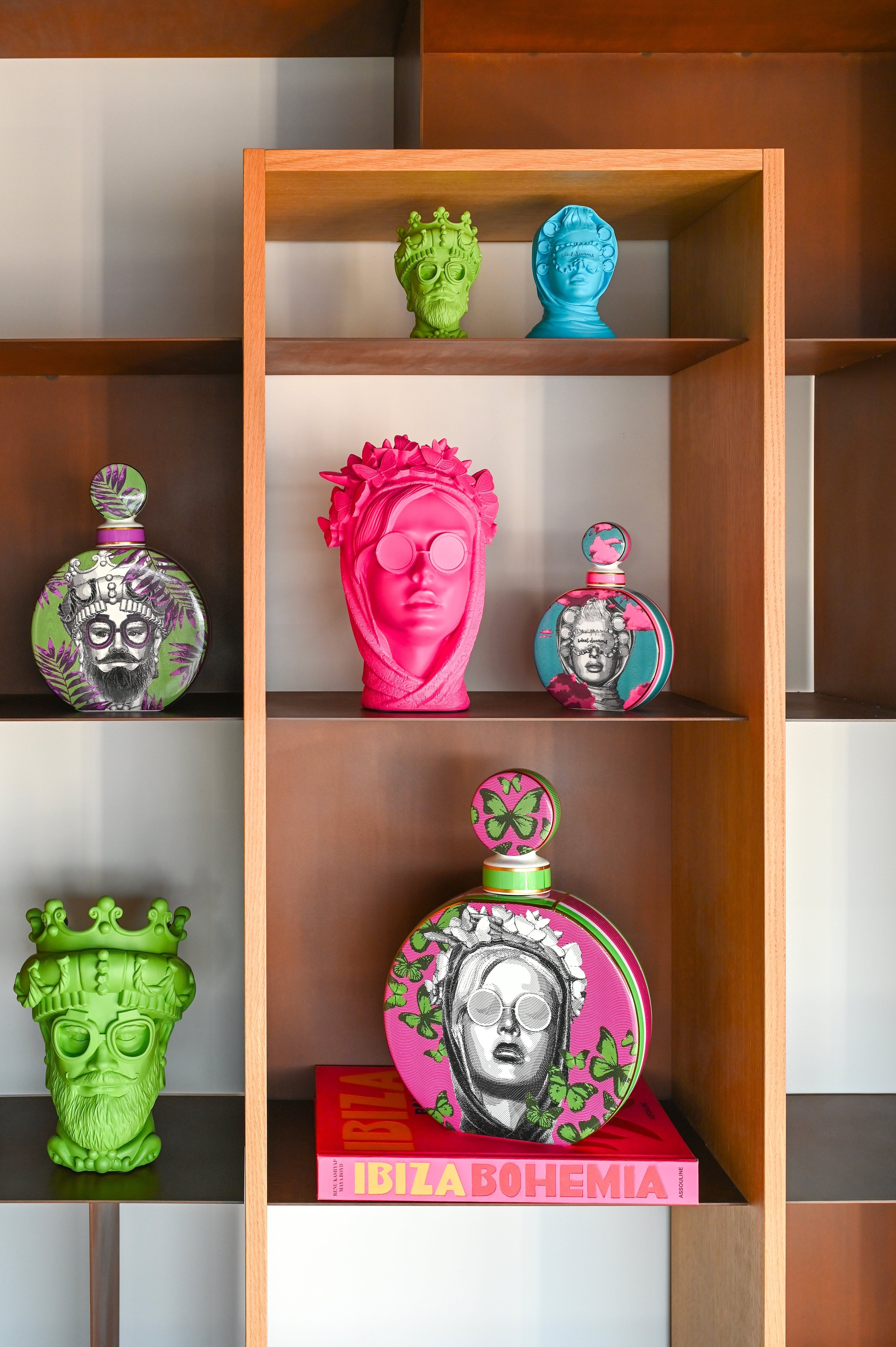 Colourful Italian pop-art head vases in pink, green and blue arranged as sculptural statement pieces on warm wood shelving