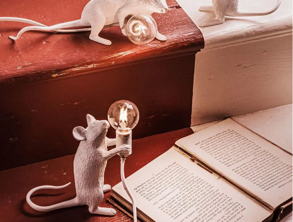 Mouse lamps on stairs — white resin mice holding bulbs as reading lights, warm glow — curated by Amprio Milano.